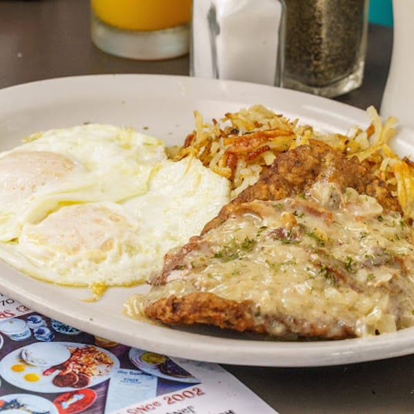 Slim Goodies Diner's chicken fried steak with gravy, hash browns, and two fried eggs.