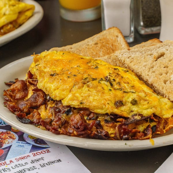 A Slim Goodies Diner omelet with cheese and herbs, bacon, and toast on a white plate.