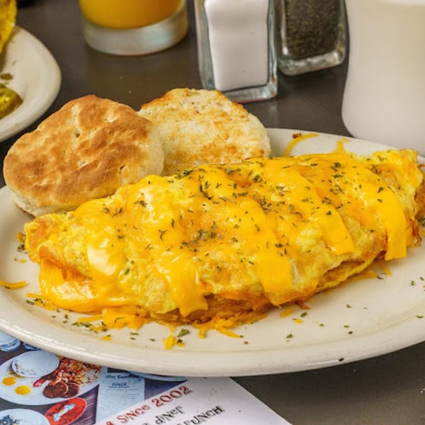 A cheesy omelet with two biscuits on a white plate at Slim Goodies Diner.