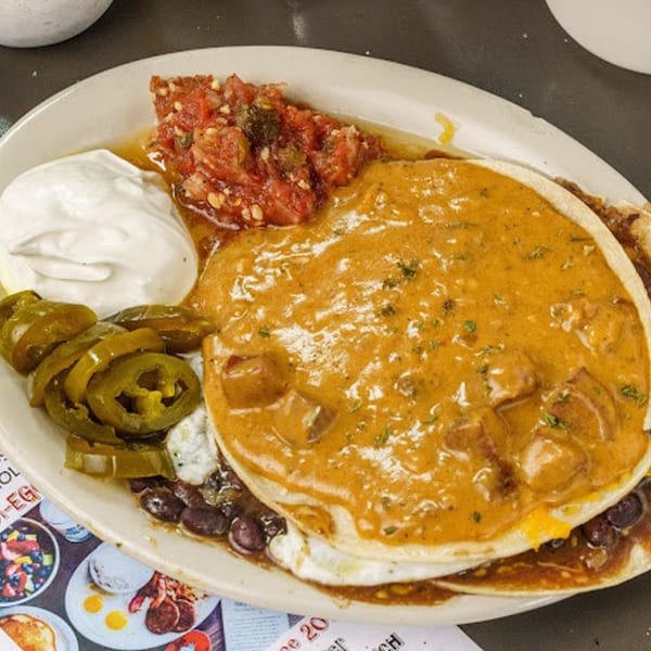 A Slim Goodies Diner breakfast plate with huevos rancheros, salsa, sour cream, and pickled jalapeños.
